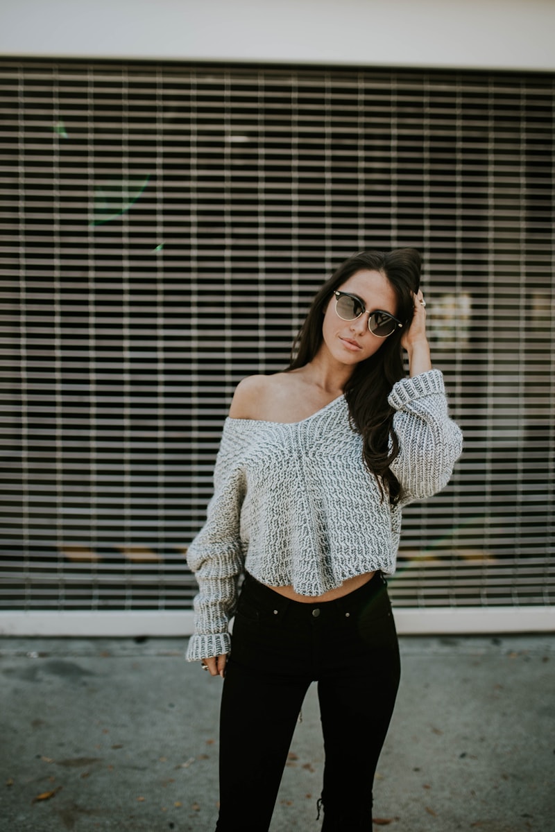 Full length figure in oversized knitwear and dark trousers against a shuttered façade